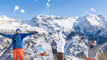Winter sports scene at Pelvoux Vallouise ski resort in Hautes-Alpes, France, featuring a skier and group of people skiing.