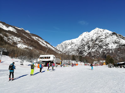 Winter scene at Pelvoux Vallouise featuring a lively sports centre amidst snow-draped chalets, in the heart of the ski resort with striking winter landscape in the backdrop.
