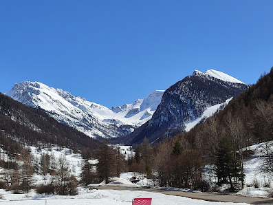 Winter scene at Ceillac en Queyras, France, showcasing a charming chalet against a backdrop of majestic mountains. Visible signs of a ski resort suggest popular winter sports activities.