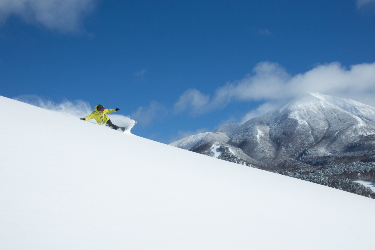 Aizu Kogen Takatsue in Japan - a person riding a snowboard down a snowy slope.