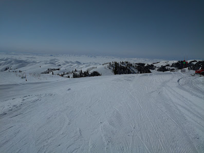 A skier glides down the snowy slopes of Soldier Mountain Ski Resort in Fairfield Idaho surrounded by imposing mountain ranges. The ski lift and a chalet in the background complete this winter sports scene.