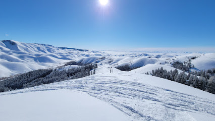 A skier enjoying a winter day at Soldier Mountain ski resort in Fairfield Idaho with snow-covered chalet in the backdrop amidst beautiful winter scenery.