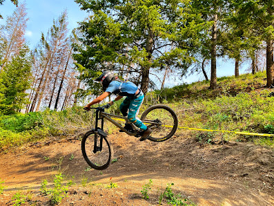A mountain biker is making their way across the striking landscape of Soldier Mountain in Fairfield Idaho a quaint challet subtly present in the distance.