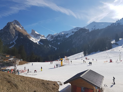Winter sports enthusiasts enjoy the day at a ski resort in Bernex, Haute-Savoie Mont Blanc, France. The picturesque scene includes a charming challet and towering mountain peaks.