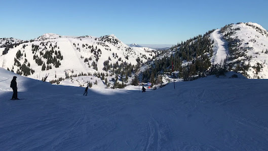 Skier enjoying a run at the Hochkar Bergbahnen ski resort in Austria, with a chalet and ski lift in the backdrop against a winter sports scene.