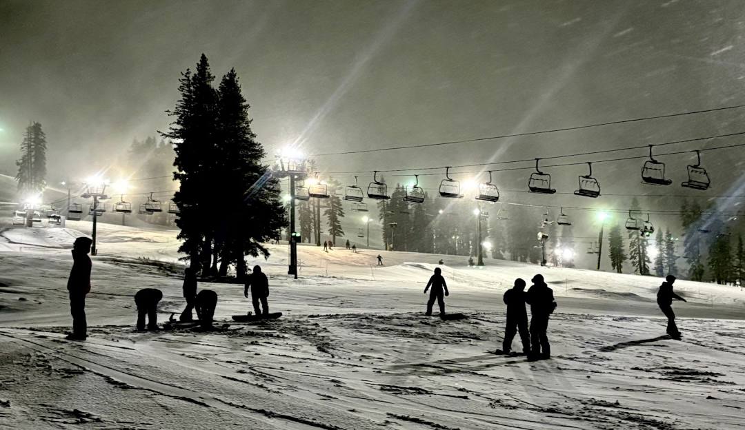 Boreal Mountain California in USA - a group of people skiing down a snowy slope at night.