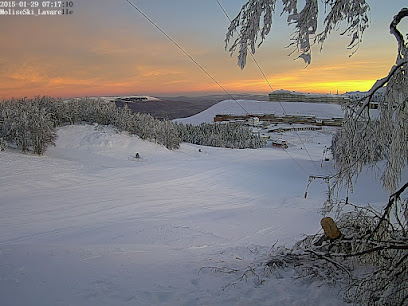 Winter scene at Campitello Matese ski resort in Italy, featuring a charming chalet amidst stunning snow-covered slopes and trees, highlighting winter sports activities.
