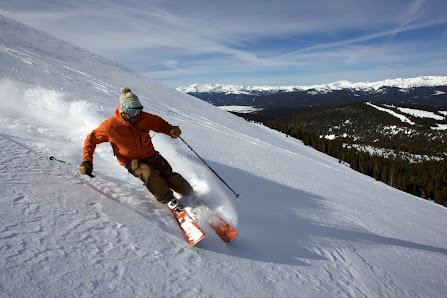 A skier and a snowboarder navigate the snowy terrain at Cooper ski resort in Leadville Colorado participating in winter sports amidst a beautiful winter landscape.
