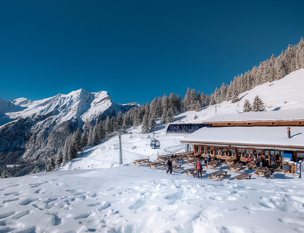 Oeschinensee in Switzerland - a restaurant in the snow with mountains in the background.