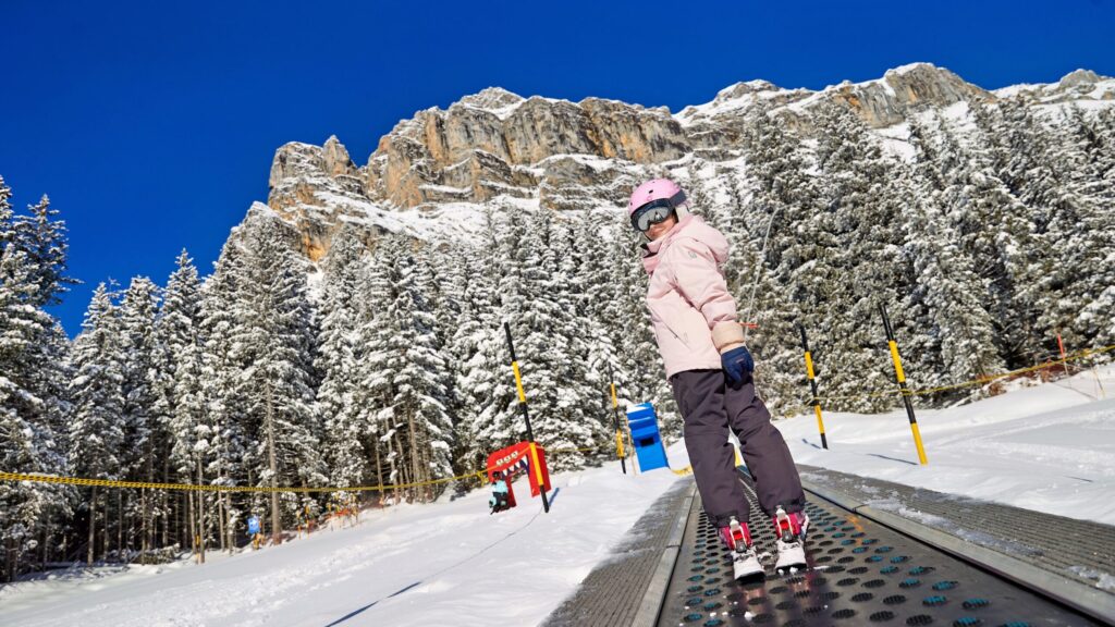 A winter scene at Oeschinensee in Switzerland showing a ski lift and a skier. The landscape is part of a bustling ski resort suggesting an exciting day of winter sports ahead.