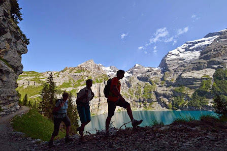 View of the serene Oeschinensee Lake nestled in the mountains of Bernese Oberland, Switzerland. A challet peeks through the wintry landscape, hinting at nearby ski resorts.