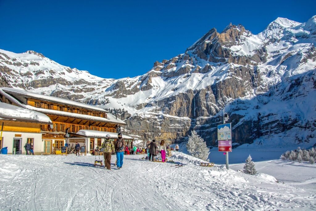 Winter scene at Oeschinensee in Bern, Switzerland showcasing a bustling ski resort, a charming chalet in the midst of snow-covered terrain, captured through the lenses of winter sports enthusiasts.