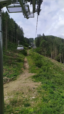 Ski lift ascending towards a rustic chalet nestled among towering peaks at the Monte Agudo ski resort in Auronzo di Cadore, Italy.