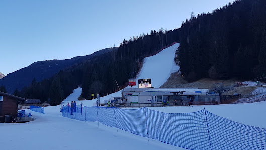 Winter sports enthusiasts enjoying a day at the Monte Agudo ski resort in Auronzo di Cadore, Italy, featuring a charming chalet and breathtaking winter scenery.