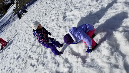 Winter sports scene at Mt. High East, Wrightwood, CA, showcasing a chalet and a ski lift. Skiers enjoying the snowy slopes.