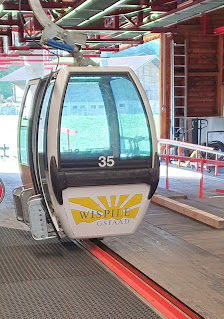 View of Wispile – Gstaad in Switzerland showcasing a prominent ski lift ascending a snow-covered mountain with hints of ski resort activity in the backdrop.