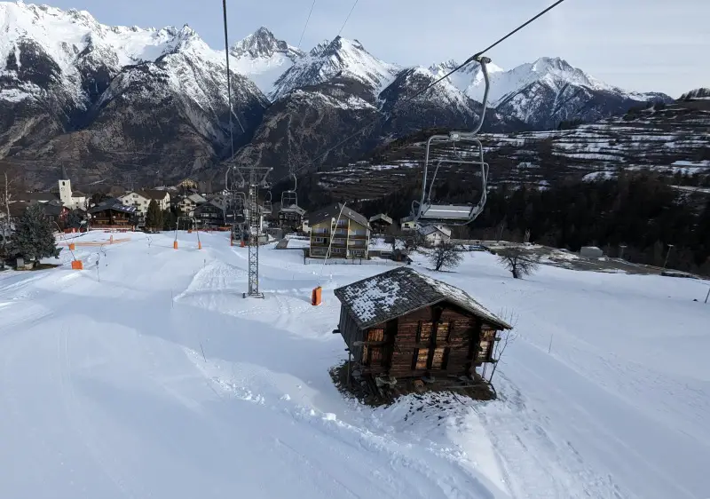 Winter sports enthusiasts enjoying at the ski resort in Unterbach, Valais, featuring a chalet amidst stunning, snowy scenery in Switzerland.