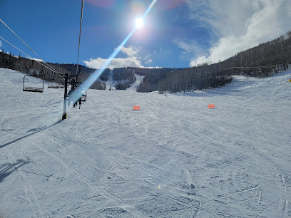 A skier enjoying a winter day at Sunlight Mountain ski resort in Glenwood Springs Colorado. A ski lift and picturesque mountains add to the scenic snowy landscape.