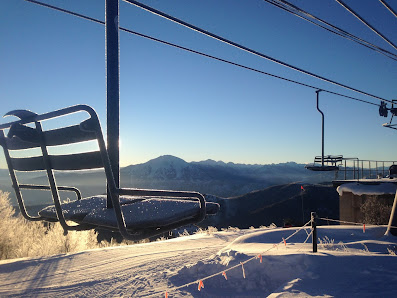 Ski lift ascending up Sunlight Mountain at a ski resort in Glenwood Springs, Colorado. A skier can be seen amongst the winter sports scene, with a chalet nestled in the background.