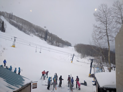Ski resort at Sunlight Mountain in Glenwood Springs, Colorado with winter scenery in full view. Winter sports enthusiasts are in motion alongside a ski lift, with a small challet visible in the backdrop.