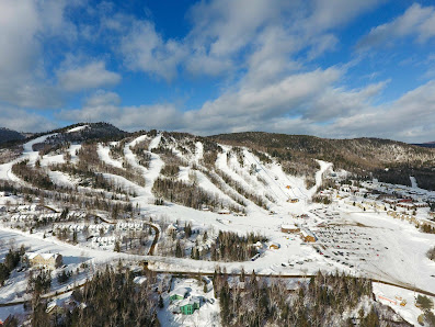 Image of Val Saint-Come ski resort in Quebec, Canada, showing a picturesque winter scene with snow-covered slopes and a ski lift used for winter sports activities.