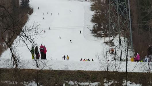 Winter sports activity at Kouty nad Desnou in the Czech Republic, featuring skiers enjoying the slopes, a visible ski lift, and the ski resort in the background.