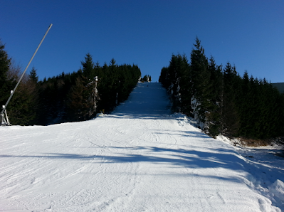 Scenic view of a chalet nestled in Kouty nad Desnou, Czech Republic. Winter sports enthusiasts enjoy the ski slopes, ski lifts accentuating the atmosphere of the popular ski resort.