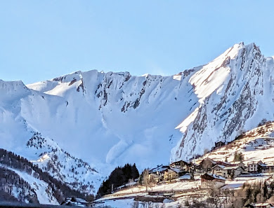 View of the Crévacol ski resort in Italy, with a charming chalet nestled against the backdrop of a snow-covered mountain. Winter sports enthusiasts can be seen enjoying the facilities.