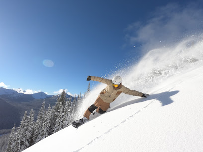 A skier and snowboarder enjoying a winter sports scene at Manning Park, a ski resort in Vancouver, British Columbia, Canada. A snowmobile is also visible amidst the scenic snowy backdrop.