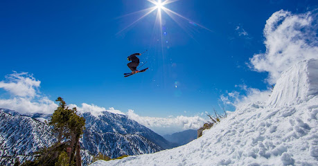 A snowboarder and skier enjoying a winter sports scene on a sunny day at the Mt Baldy ski resort in California USA. The mountain is coated with snow creating a beautiful and fun environment for winter sports enthusiasts.