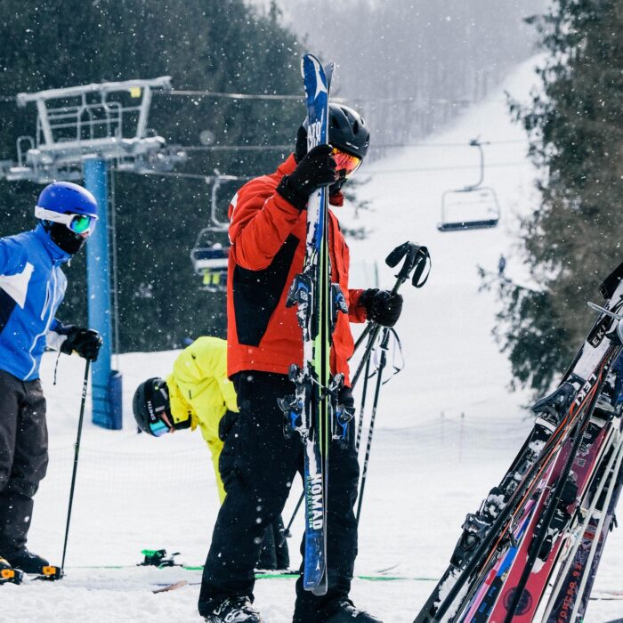 A skier enjoying a run at Holimont, a ski resort in Ellicottville, New York, with a ski lift and bustling winter sports activities in the background.