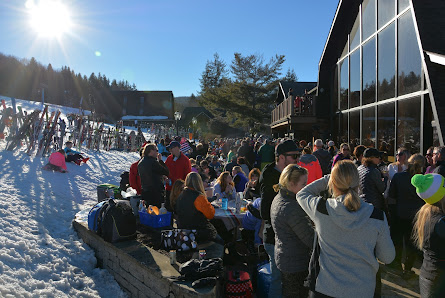 Winter sports scene at Holimont in Ellicottville, New York, featuring a bustling winter sports center, a ski resort with a functioning ski lift, and a cozy chalet nestled in the snow.