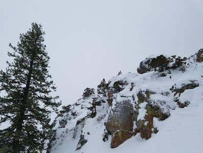A skier enjoying a winter sports scene at Pebble Creek Inkom Idaho on a mountain landscaped with a hint of snow and a quaint chalet in the background.