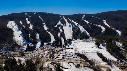 A picture featuring Butternut ski resort in Great Barrington Massachusetts showcasing snow-covered slopes bustling with winter sports enthusiasts. A chalet is visible in the distance.