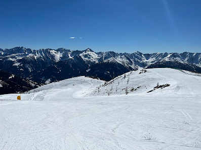 A skier navigates down slopes at the Obertilliach-Golzentipp ski resort in Austria with a charming chalet and ski lift subtly appearing in the winter sports scene.