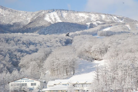 A breathtaking winter scene at Miyagi Zao Eboshi Resort in Japan, featuring a bustling ski resort nestled in the crisp white snow amid mountainous terrain.