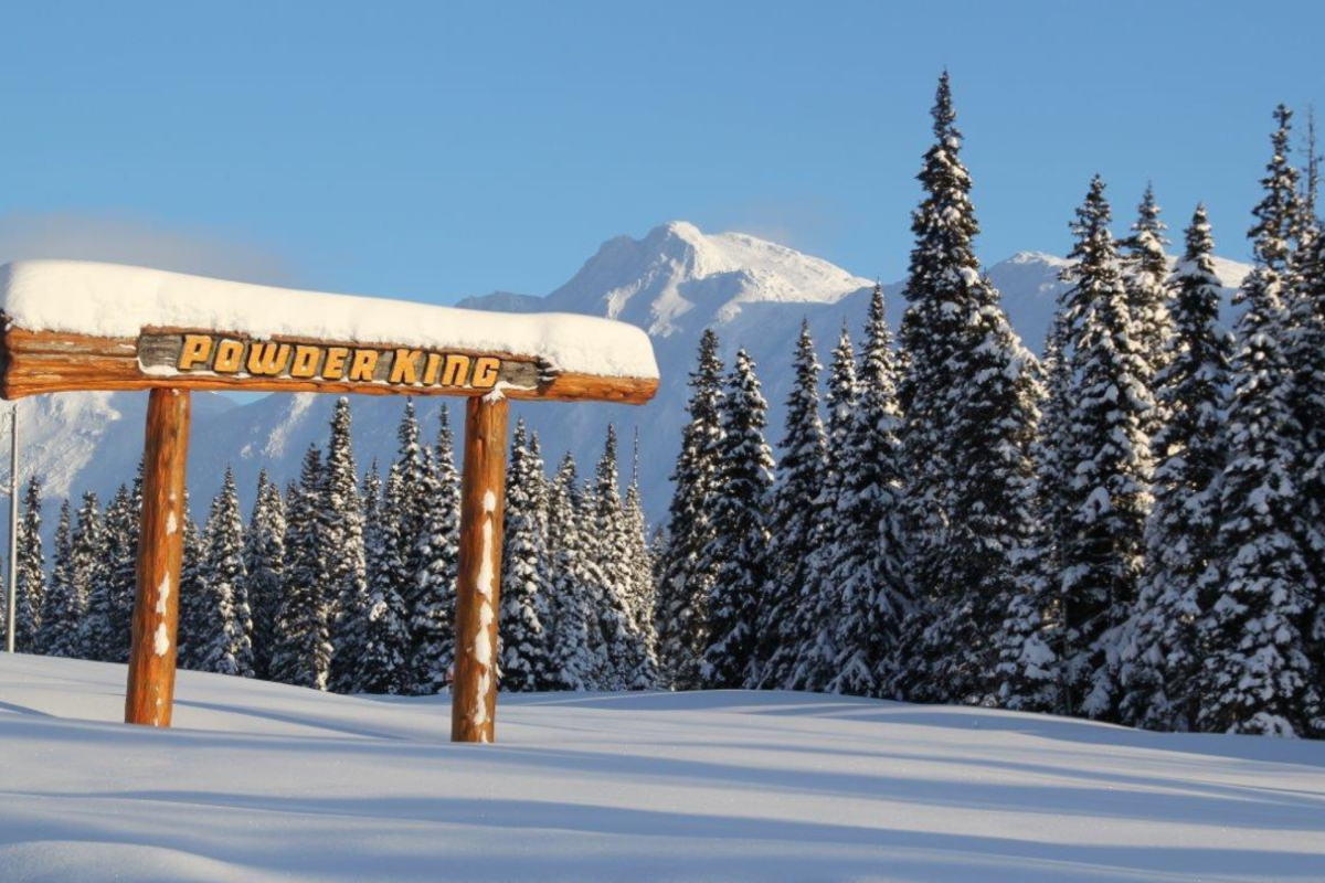 Powder King in Canada - a wooden sign in the snow with mountains in the background.