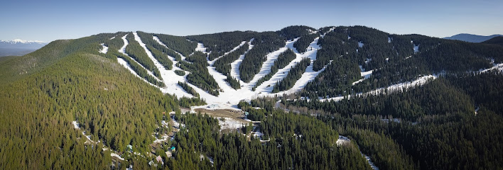 View of Purden Ski Village in British Columbia, Canada, featuring a ski resort with a ski lift against snow-covered slopes. Skiers enjoy the winter sports scene.