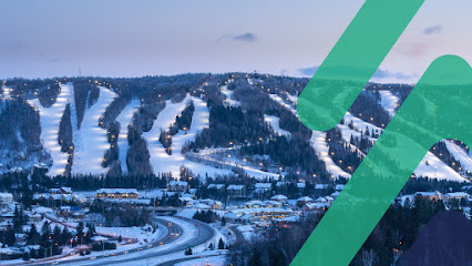 A skier enjoying a run down the snow-covered slopes of Saint-Sauveur Summit in Piedmont Quebec Canada beside a ski lift. The ski resort is a popular winter sports scene.