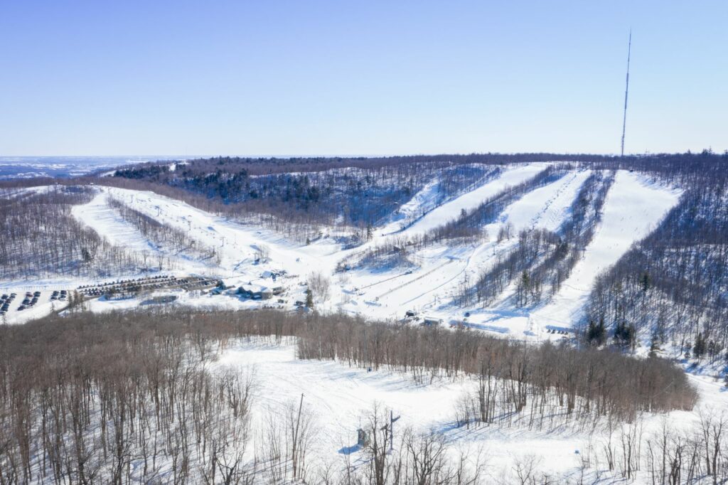 Winter sports enthusiasts enjoying the snow-covered slopes at Camp Fortune, a ski resort in Chelsea, Quebec, Canada, amidst breathtaking winter scenery.