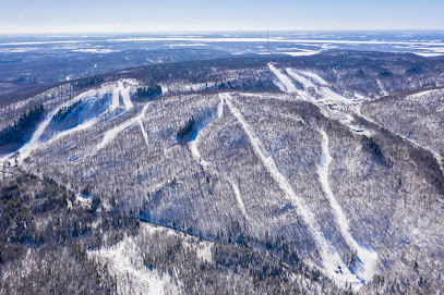 View of Camp Fortune ski resort in Chelsea Quebec featuring a ski lift and snow-covered slopes. Skiers engage in winter sports activities amidst a white wintry landscape.