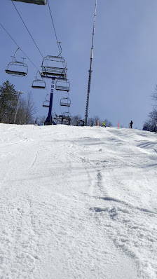 A skier glides down a snowy slope at Camp Fortune in Chelsea, Quebec, Canada. A ski lift operates in the background, contributing to the winter sports scene at this popular ski resort.