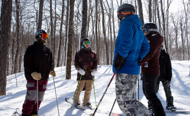 Winter sports scene at Camp Fortune, Chelsea, Quebec, showing a family and a group of people engaging in skiing at the popular ski resort.