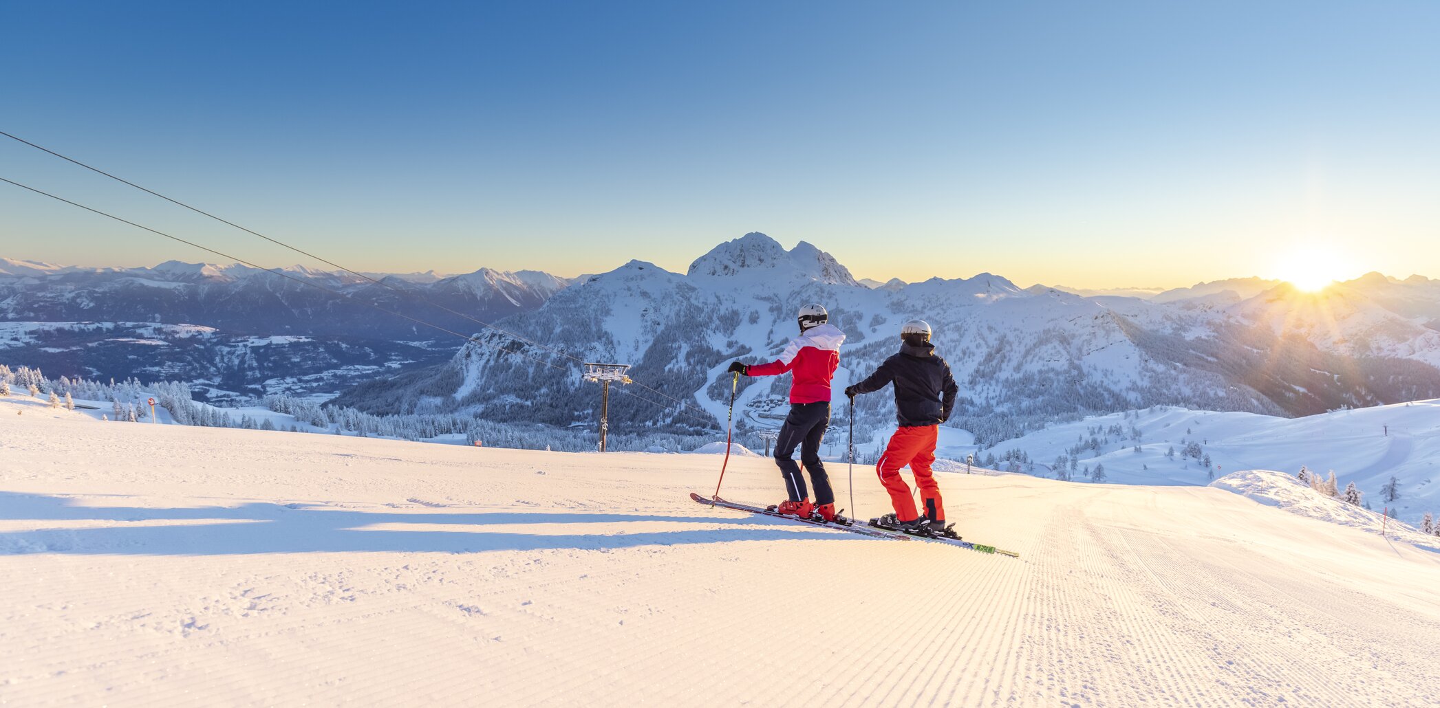 Winter sports scene at Nassfeld ski resort in Austria, with a skier and groups of people, including a family, enjoying a day of skiing.