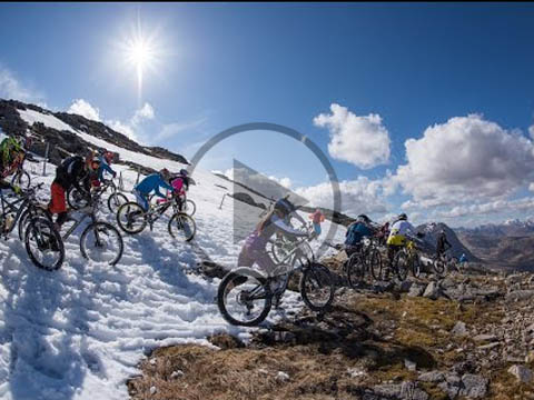 Winter sports scene at Glencoe Mountain, with a mountain bike in the foreground and a chalet and sports centre visible in the background.