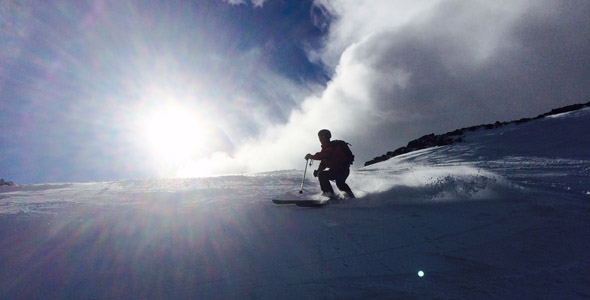 A skier and a snowboarder enjoying winter sports at Glencoe Mountain, a popular ski resort in the Highlands of Scotland, framed by the quaint scenery of chalets and pristine snow.