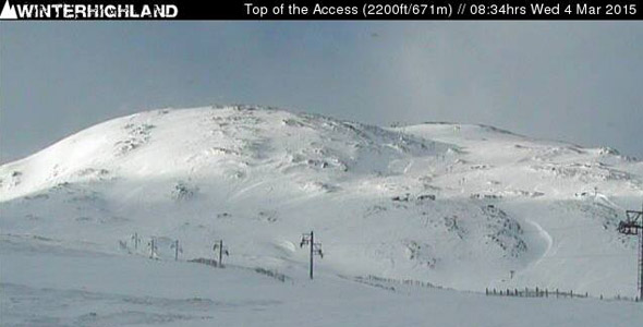 Overlooking Glencoe Mountain in the Scottish Highlands a ski resort is nestled amidst snow-covered slopes. A lone skier is visible against the vast mountainous backdrop emphasizing the beauty and scale of the snowy scenery.