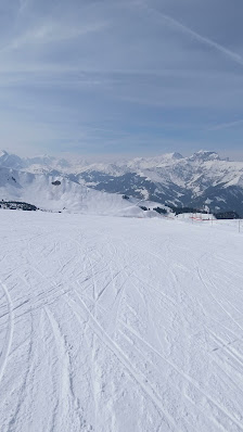 Overlooking Elsigen-Metsch ski resort in Achseten Switzerland. A chalet nestles amidst a winter sports scene with skiers navigating the snow-covered slopes.