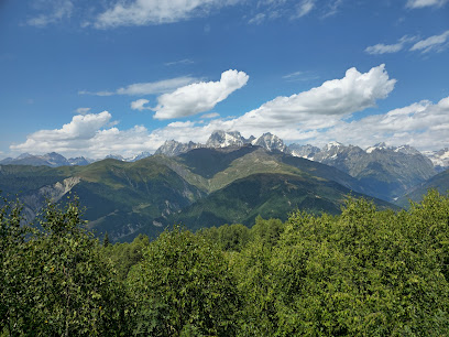 A picturesque chalet situated in the mountainous landscape of Hatsvali, Mestia in Ieli, Samegrelo-Zemo Svaneti, Georgia, on a sunny day, with a mountain bike nearby indicating the adventurous nature of the area, possibly a ski resort.