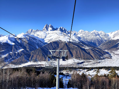 Ski lift ascending up a snow-covered mountain at the Hatsvali-Mestia ski resort in Georgia. A vibrant winter sports scene with skiers sliding down the slopes and a cozy chalet nestled at the base.